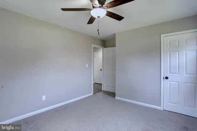 a view of an empty room and chandelier fan