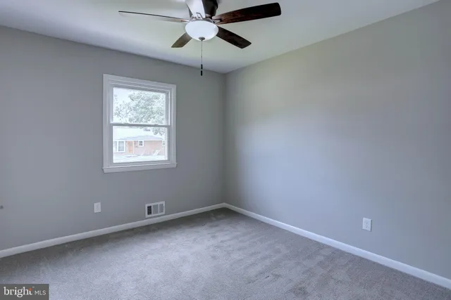 an empty room with a window and a fan