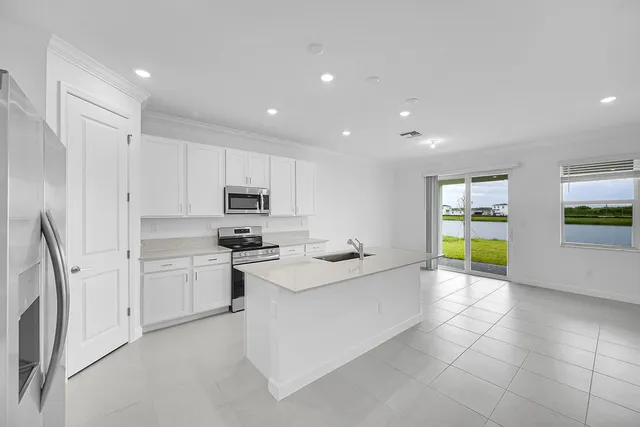 a large kitchen with a sink stainless steel appliances and cabinets