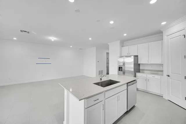 a kitchen with stainless steel appliances a sink a stove a refrigerator and white cabinets