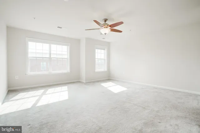 an empty room with windows and fan