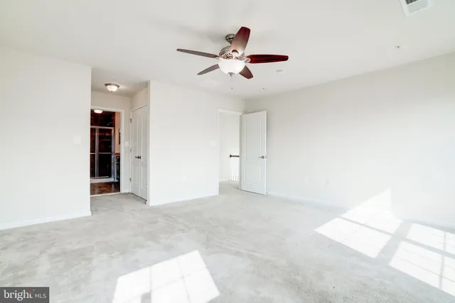 an empty room with closet and a ceiling fan