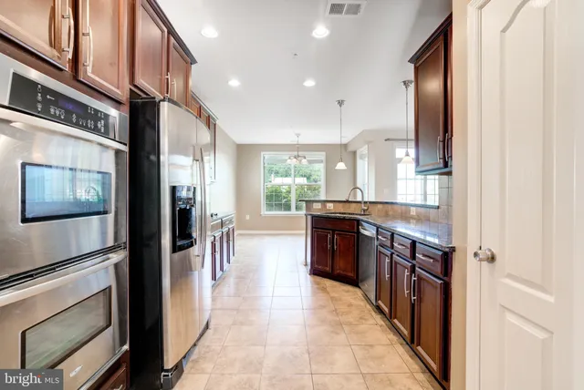 a large kitchen with stainless steel appliances granite countertop a refrigerator and a stove