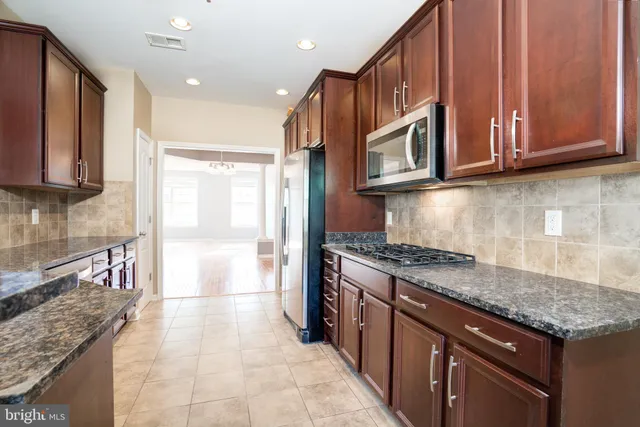 a kitchen with stainless steel appliances granite countertop a stove a sink and a microwave