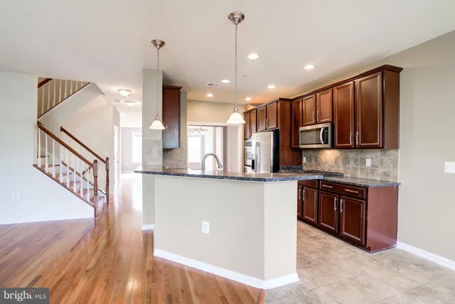 a open kitchen with stainless steel appliances granite countertop a stove a sink dishwasher and a refrigerator with wooden floor