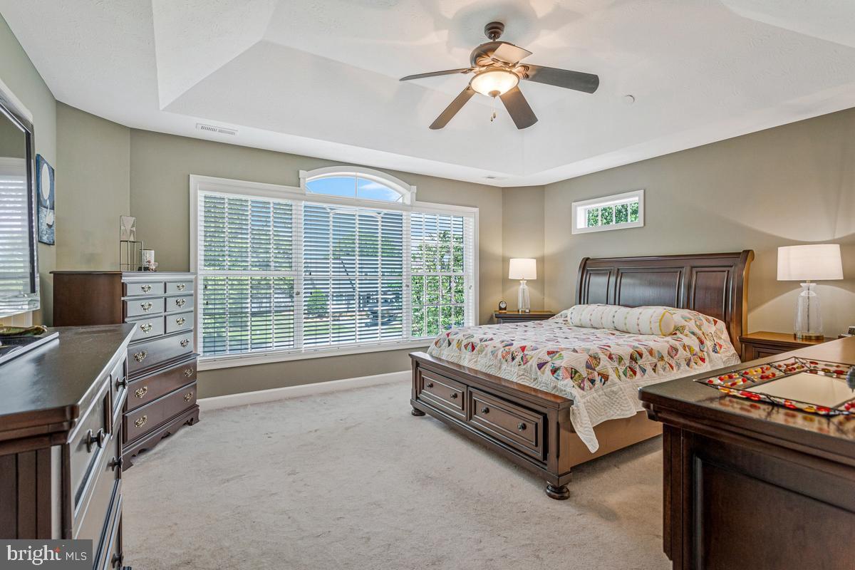 11565 Magnolia Court Issue, MD 20645 - Photo 27 of 68 a spacious bedroom with a bed and a chandelier