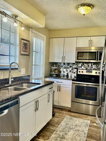 a kitchen with stainless steel appliances granite countertop a stove a sink and a microwave