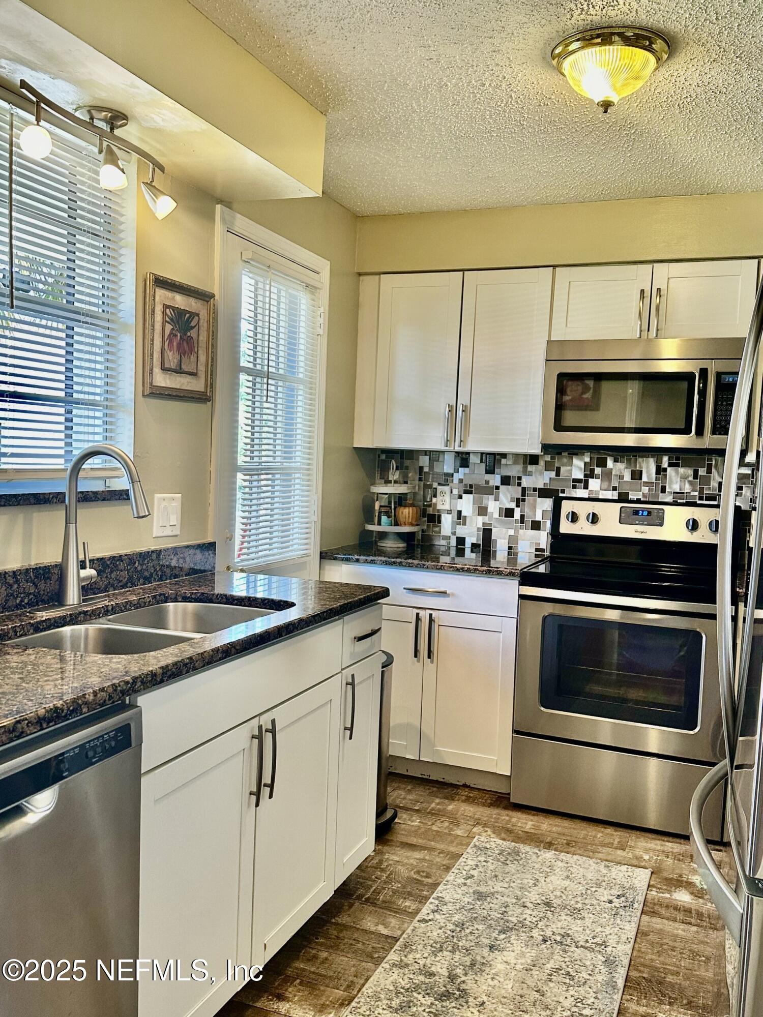 a kitchen with stainless steel appliances granite countertop a stove a sink and a microwave