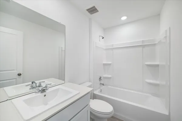 a bathroom with a bathtub shower sink vanity mirror and toilet