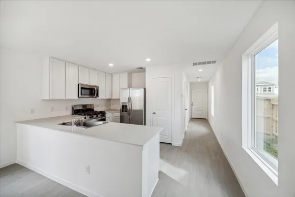 a kitchen with stainless steel appliances a refrigerator a sink a stove a microwave and white cabinets