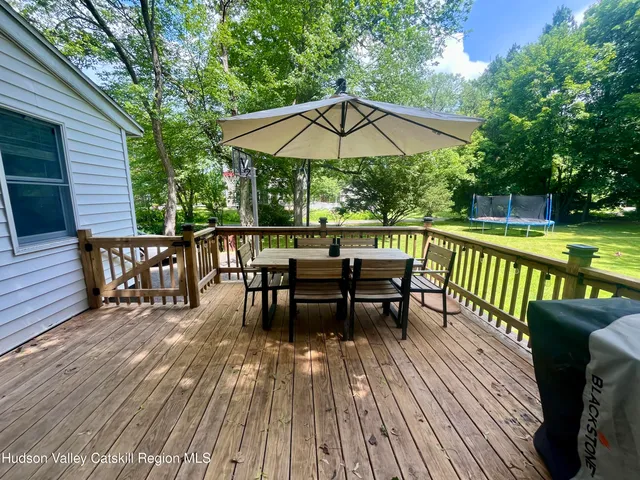 a view of a roof deck with table and chairs under an umbrella with wooden floor and fence