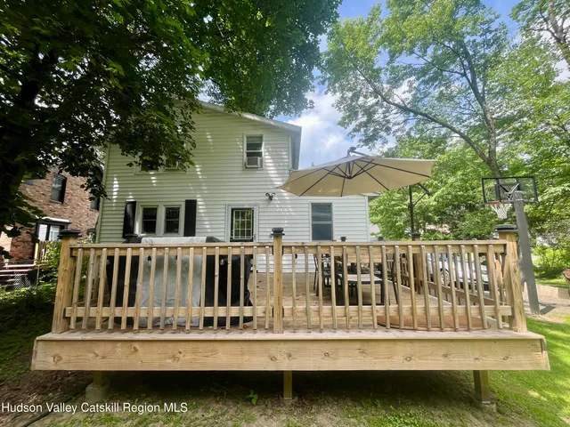 a view of a house with large trees and outdoor seating
