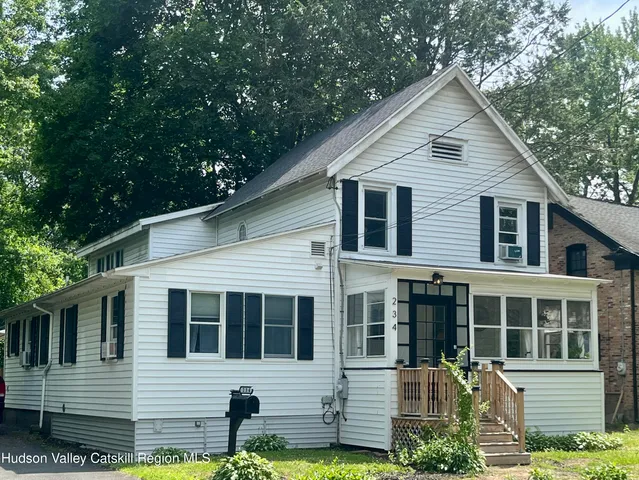a view of a white house with large windows and a small yard