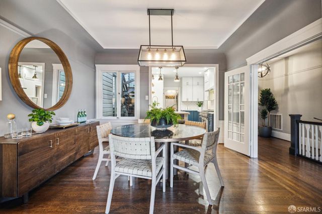 a dining room with wooden floor a chandelier a wooden table and chairs