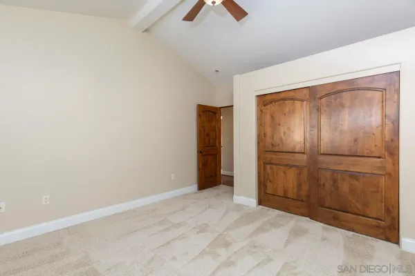 an empty room with closet and a chandelier fan