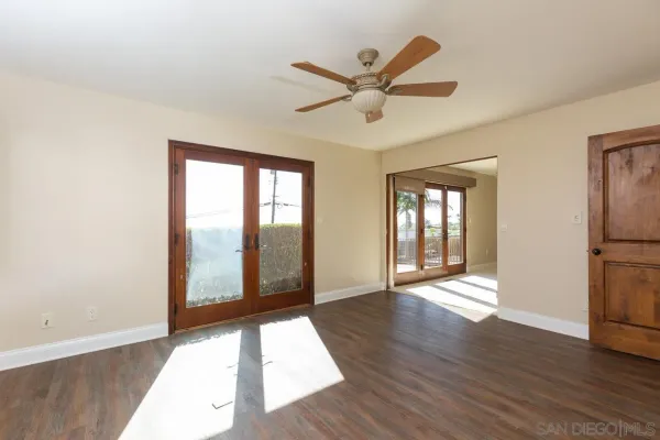 a view of an empty room with window and wooden floor