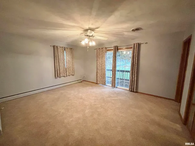 an empty room with windows and fan