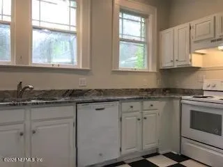 a kitchen with granite countertop white cabinets and a stove