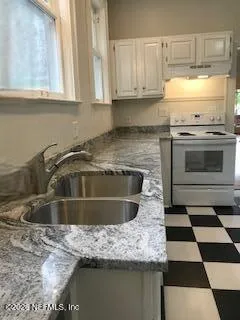 a kitchen with a sink a stove cabinets and a window