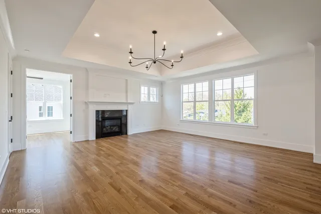 an empty room with wooden floor fireplace and windows