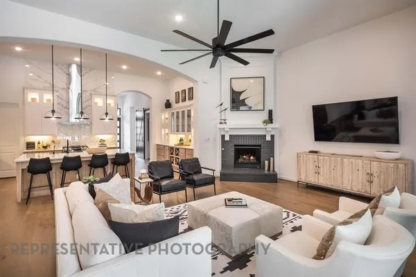 a living room with furniture a flat screen tv and kitchen view