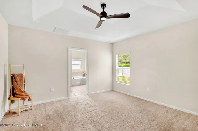 an empty room with windows and ceiling fan