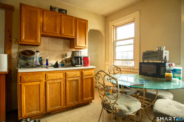 a kitchen with stainless steel appliances granite countertop a table chairs and a refrigerator