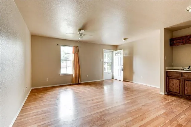 a view of an empty room with a window and wooden floor