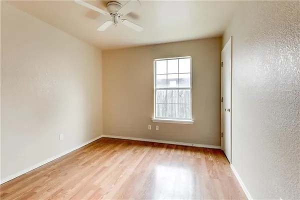 an empty room with a window and a ceiling fan