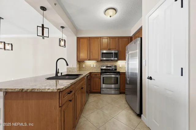 a kitchen with granite countertop a refrigerator stove and microwave