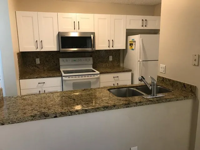 a kitchen with granite countertop a sink and a stove top oven