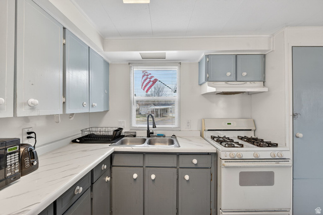 24 Grover Street Layton, UT 84041 - Photo 17 of 21 Kitchen featuring white range with gas cooktop, gray cabinetry, light countertops, black microwave, and under cabinet range hood