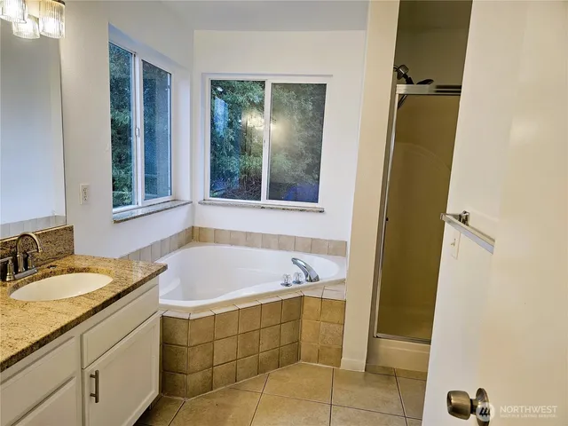 a bathroom with a granite countertop sink a mirror and a bathtub
