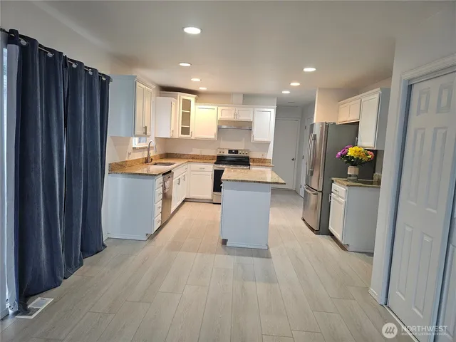 a kitchen with stainless steel appliances granite countertop a sink stove refrigerator and cabinets