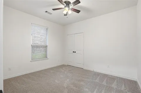 an empty room with a window and a fan