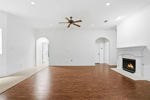 an empty room with wooden floor fireplace and windows