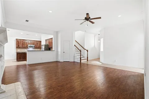 a view of a livingroom with a fireplace a ceiling fan and windows