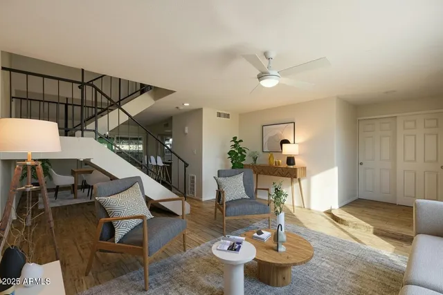 a living room with couches and a dining table with wooden floor