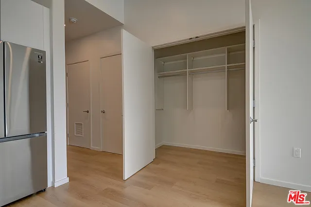 a view of an empty room with wooden floor and closet area
