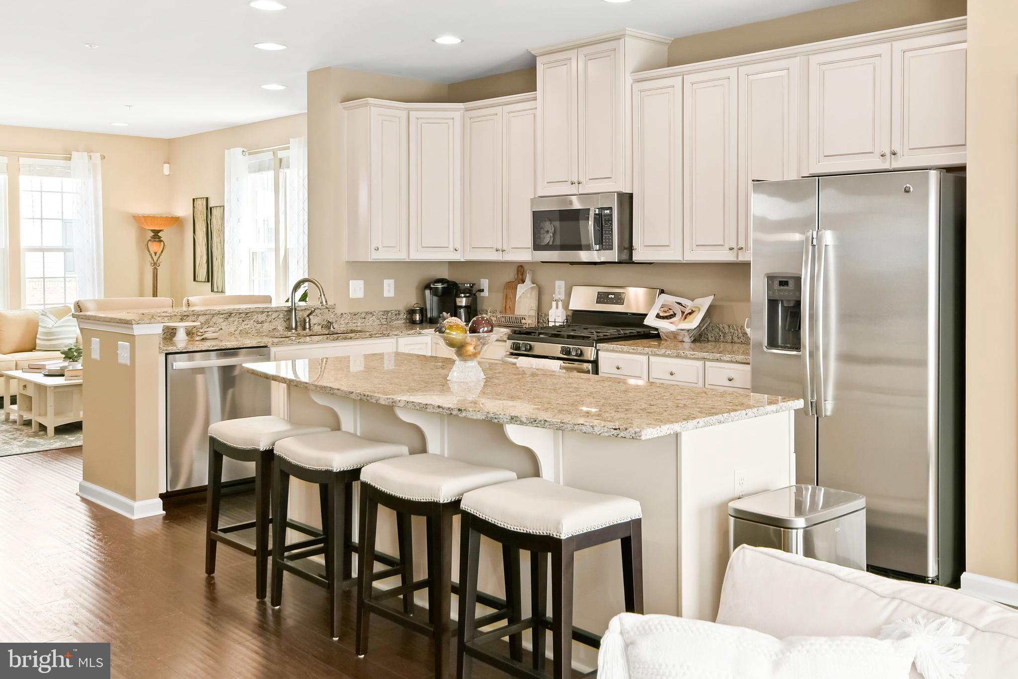 4502 Tinder Monrovia, MD 21770 - Photo 5 of 62 a kitchen with stainless steel appliances kitchen island granite countertop a dining table chairs refrigerator and sink