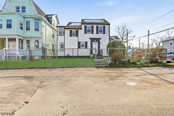 a view of a white house next to a yard with big trees