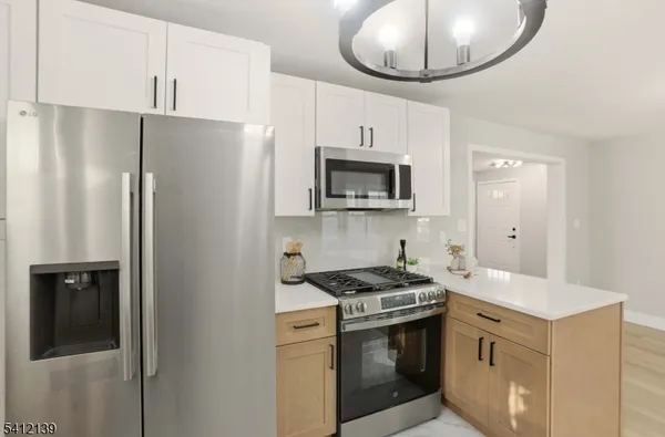 a kitchen with stainless steel appliances a refrigerator a stove a sink and a white cabinets