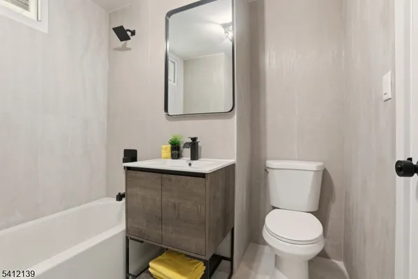 a bathroom with a toilet sink vanity tub and mirror