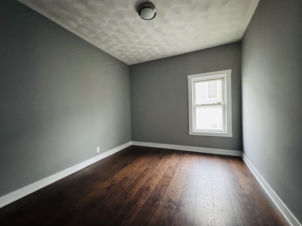 166 Bradford Avenue, Unit 3 Fall River, MA 02721 - Photo 13 of 19 an empty room with wooden floor and windows