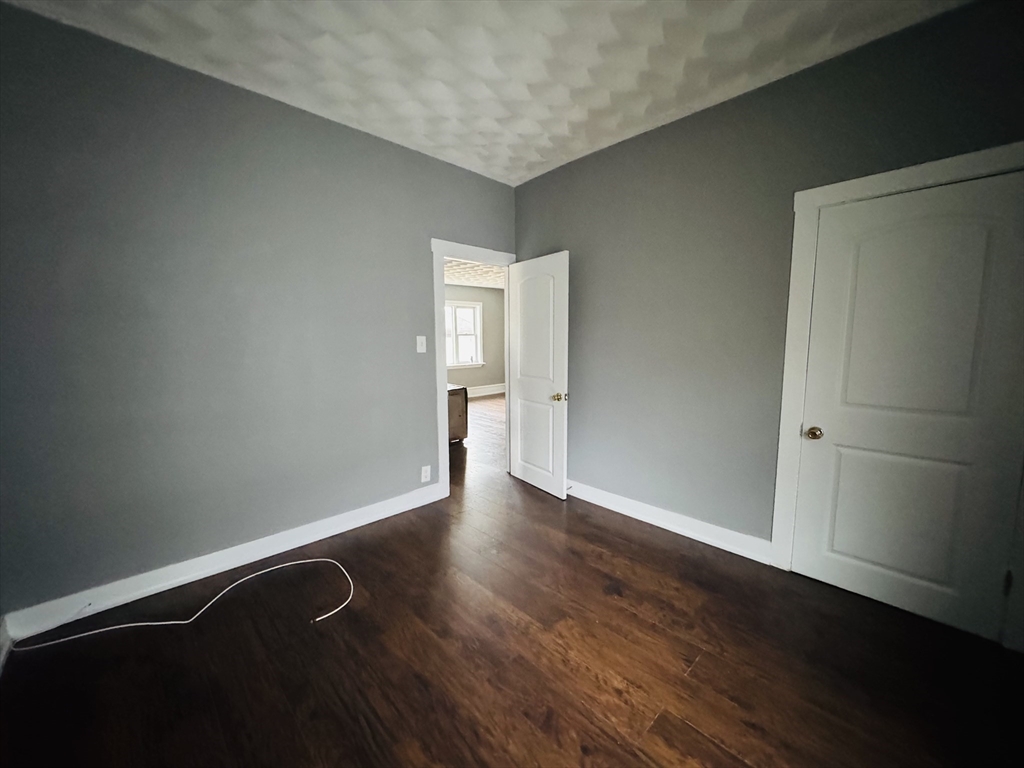 166 Bradford Avenue, Unit 3 Fall River, MA 02721 - Photo 18 of 19 an empty room with wooden floor and windows