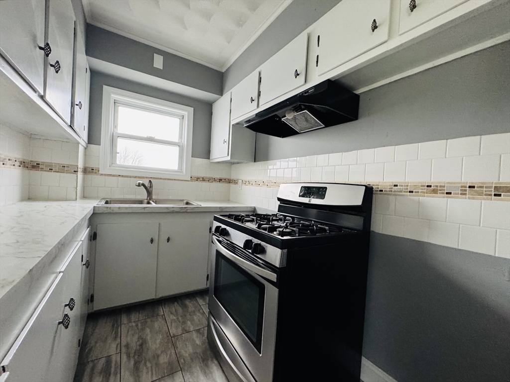 166 Bradford Avenue, Unit 3 Fall River, MA 02721 - Photo 3 of 19 a kitchen with a stove sink and cabinets