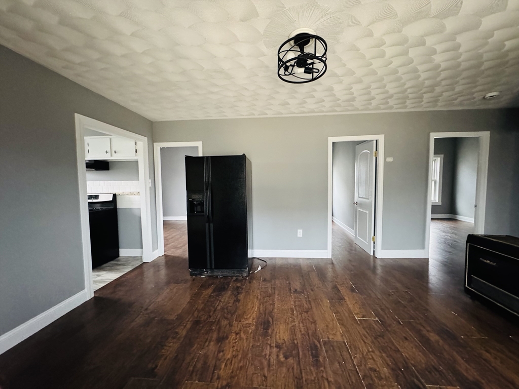 166 Bradford Avenue, Unit 3 Fall River, MA 02721 - Photo 6 of 19 a view of a refrigerator in kitchen and an empty room with wooden floor