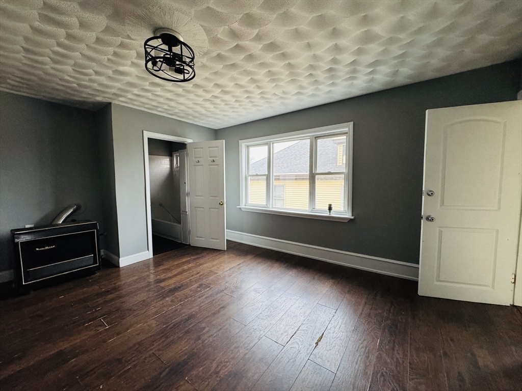 166 Bradford Avenue, Unit 3 Fall River, MA 02721 - Photo 7 of 19 an empty room with wooden floor and windows