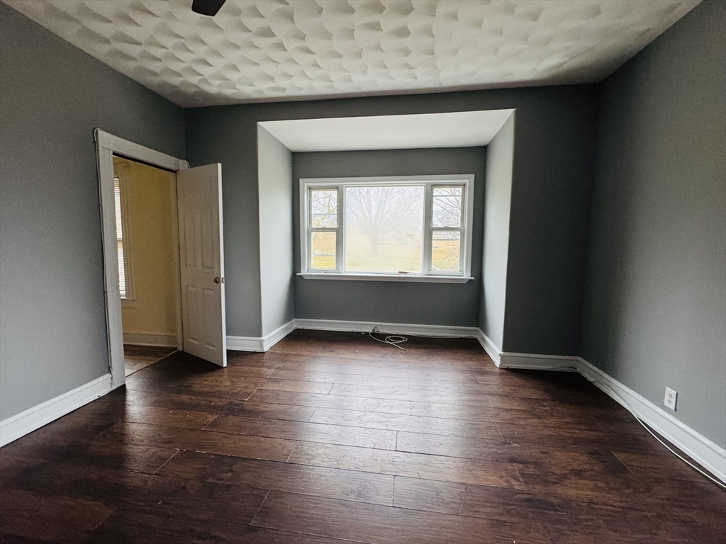 166 Bradford Avenue, Unit 3 Fall River, MA 02721 - Photo 9 of 19 an empty room with wooden floor and a window