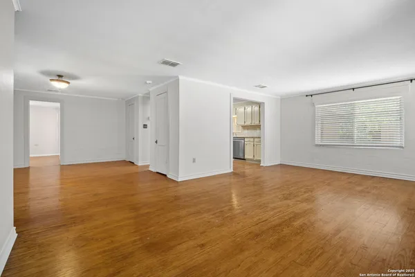 an empty room with wooden floor and windows